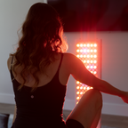 Woman sitting with a red light panel in the background