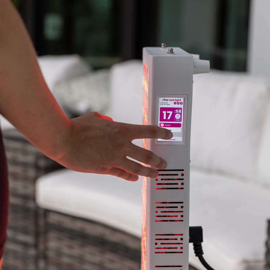 Hand clicking a screen of a red light teraphy device with a blurred background