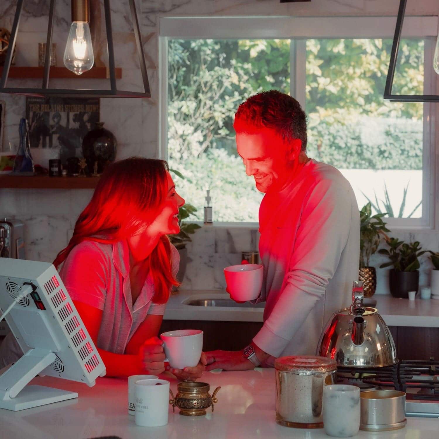 Two people in a kitchen with red lighting, one person is pouring coffee.