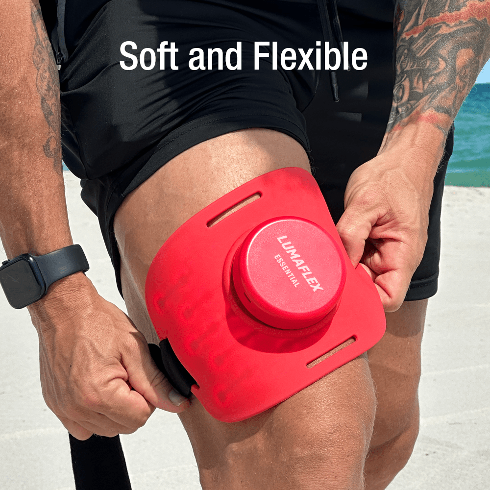 Red knee brace being worn on a person's knee with 'Lumaflex' branding, set against a beach background.