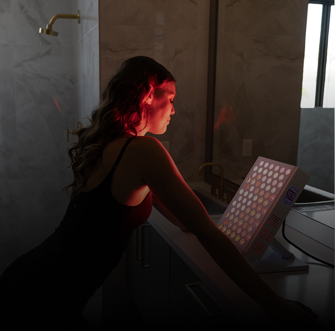 Woman using a light therapy lamp in a dimly lit room