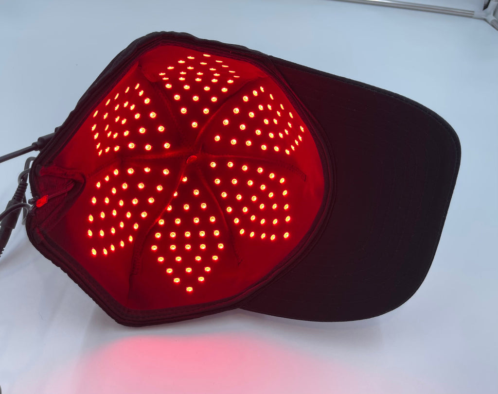 Red LED light pad on a black cap against a white background