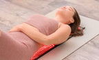 Woman lying on a red light teraphy mat on a wooden floor